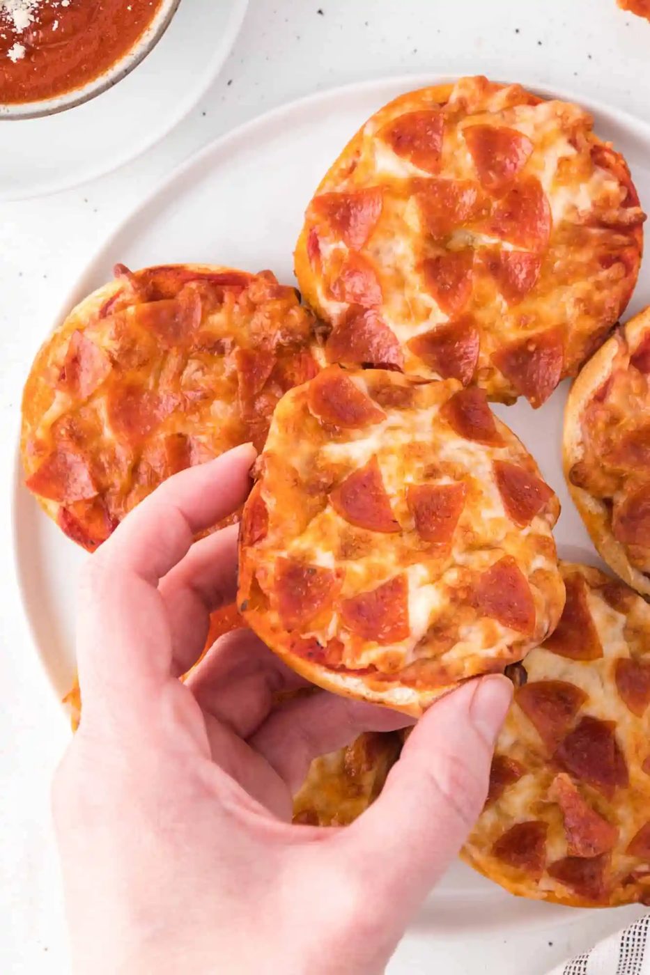 Hand holding a from-scratch bagel bite pizza.