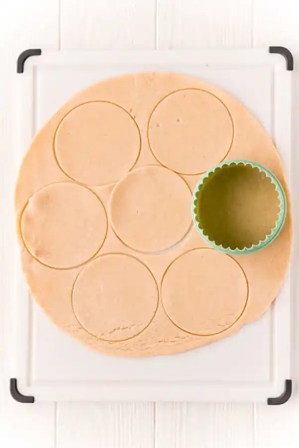 Biscuit cutter cutting a pie crust into circles.