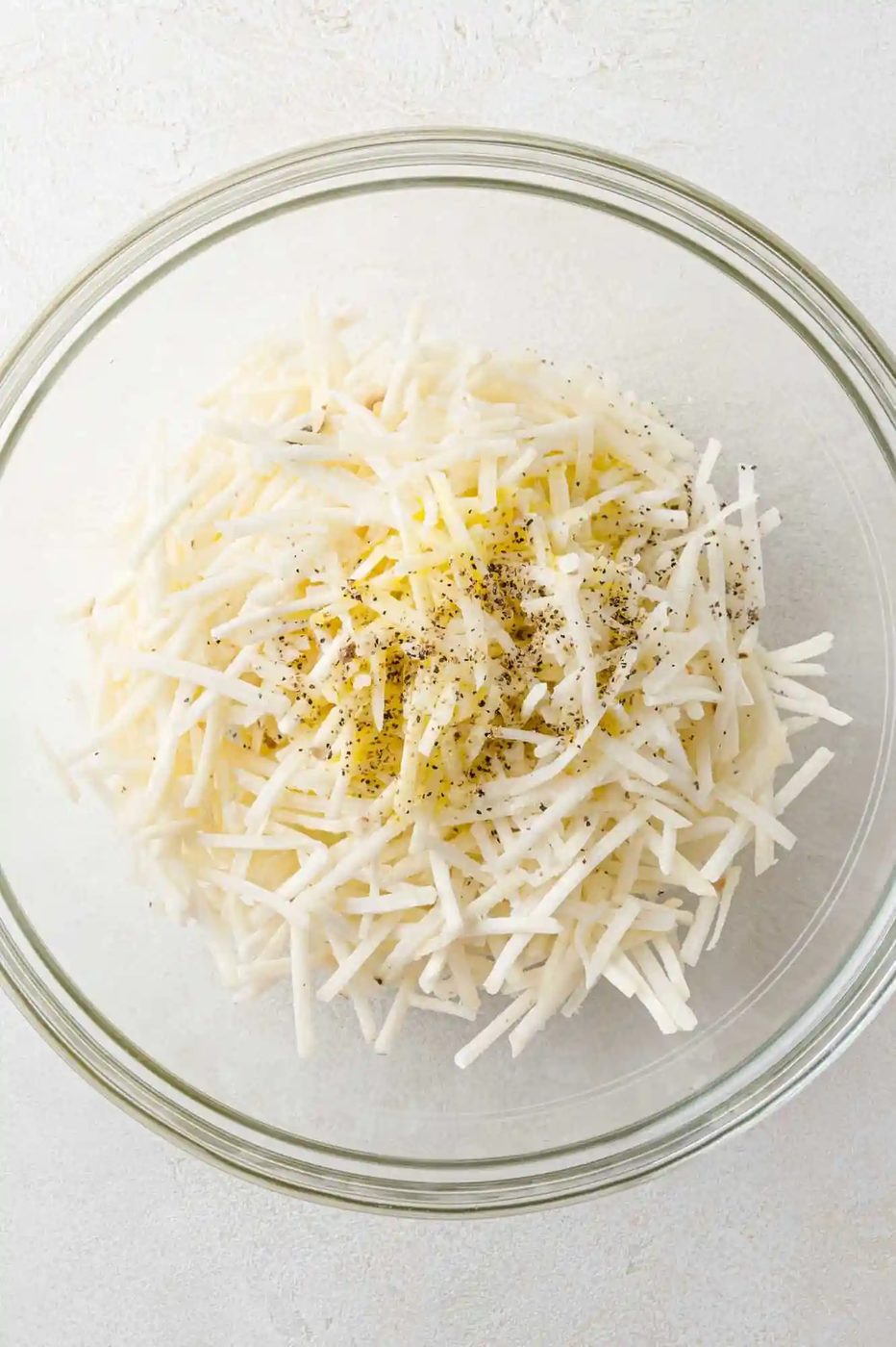 Seasoning added to frozen hash browns, not yet mixed in.
