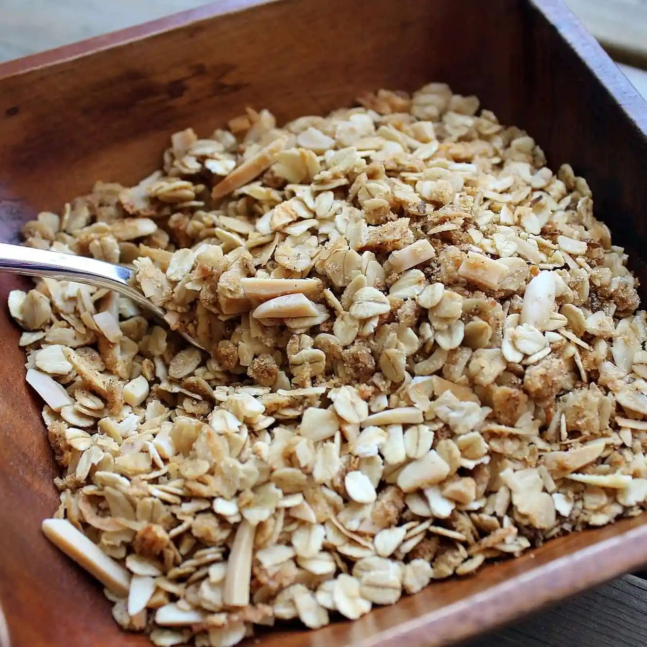 Overhead closeup of wooden bowl with granola and spoon.