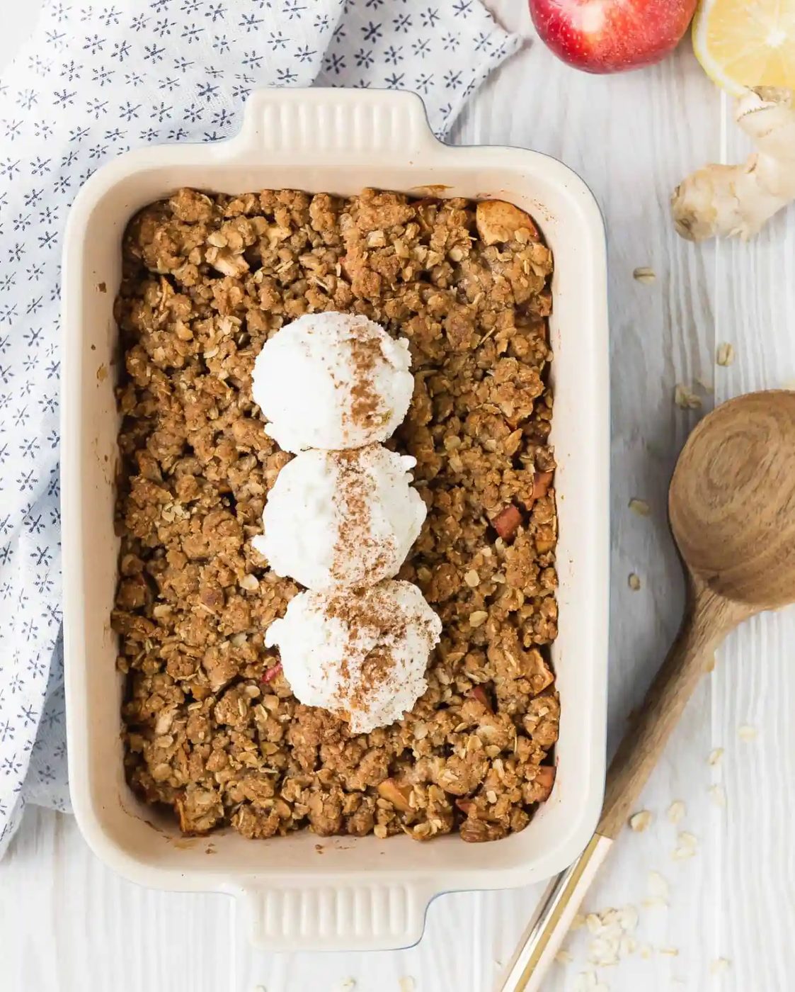 Overhead view of apple crisp in casserole dish, topped with ice cream.