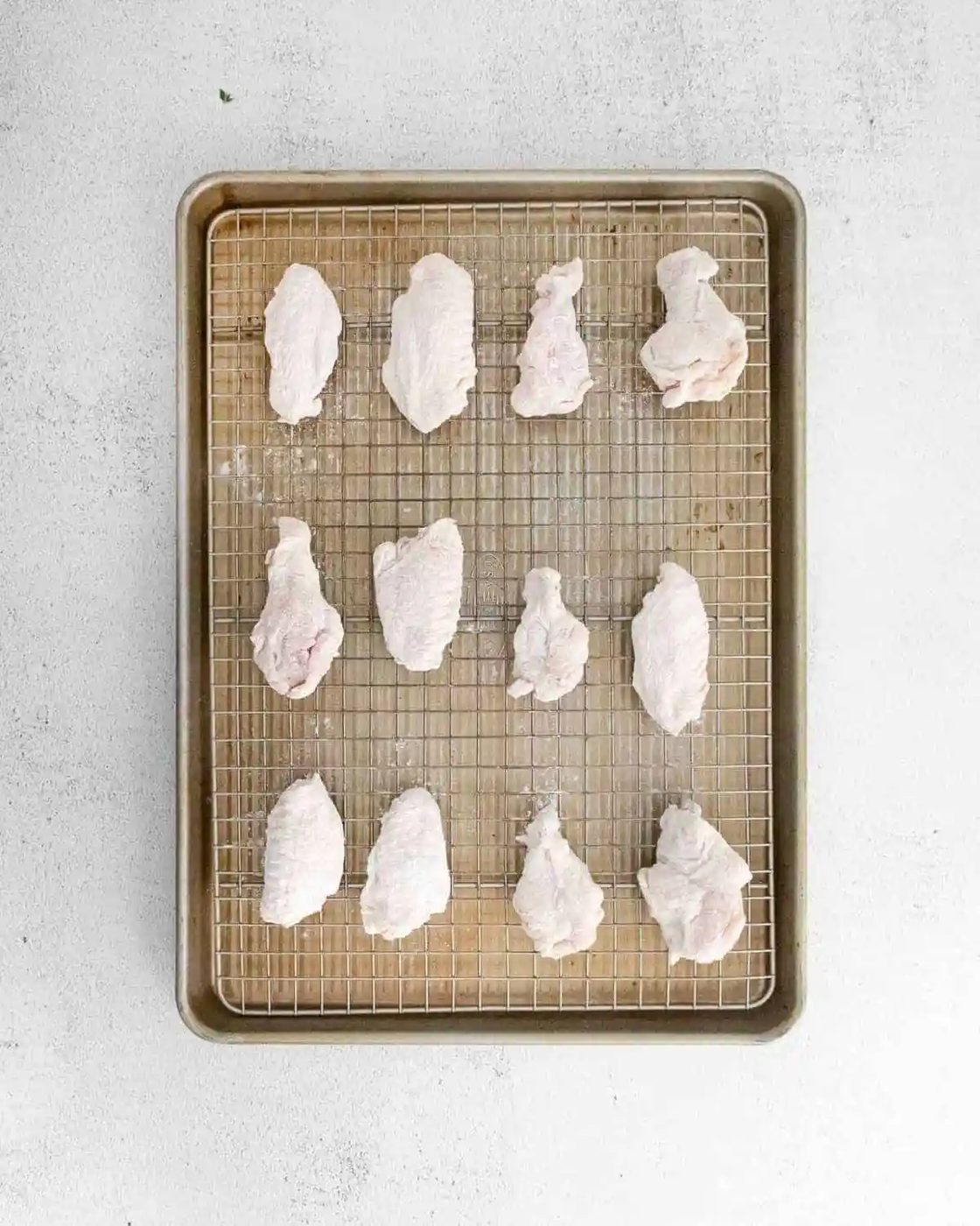 Unbaked wings on a baking sheet.