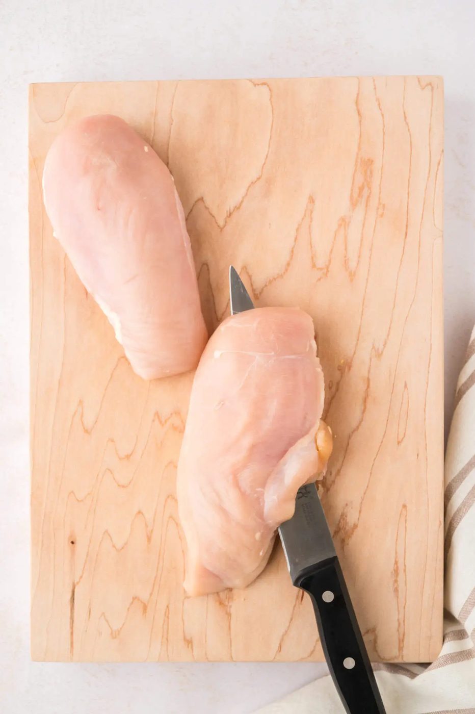 Step one of butterflying - cutting a chicken breast in half.