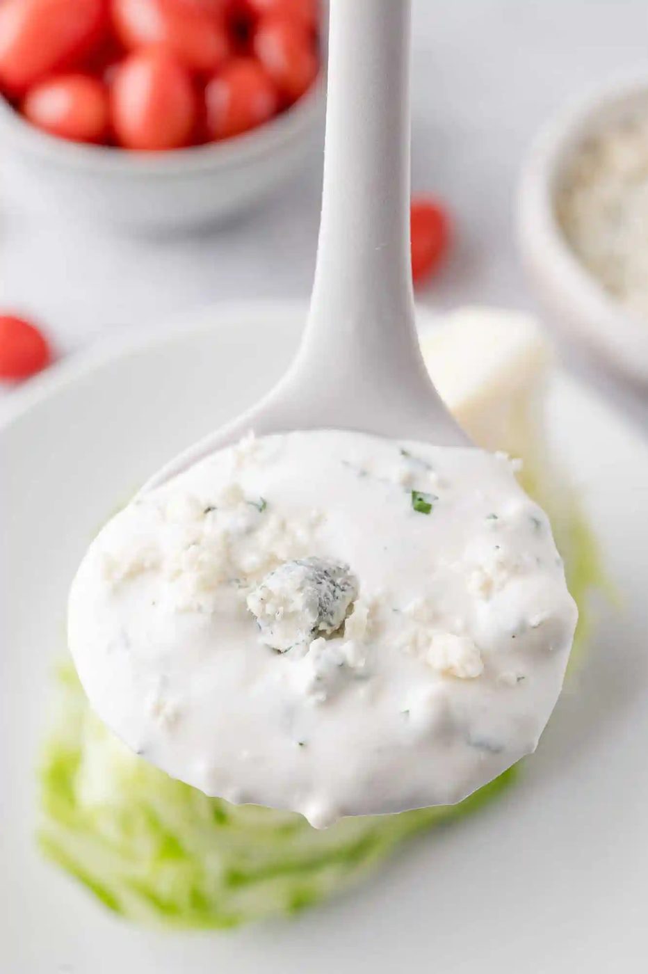 Blue cheese dressing on a small white ladle.