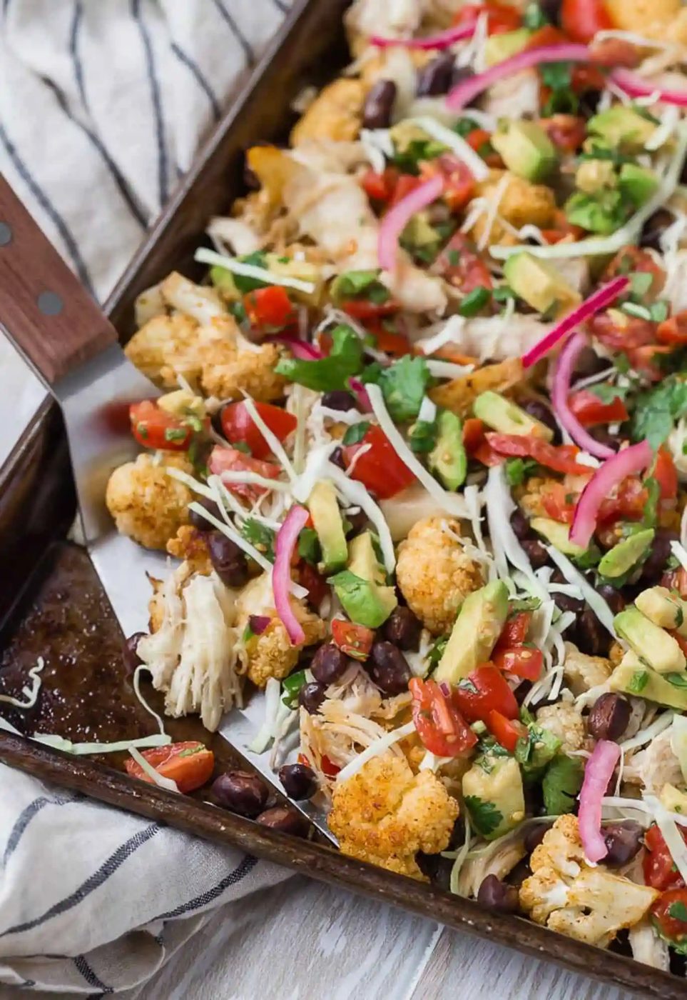 Cauliflower nachos being served with a large spatula.