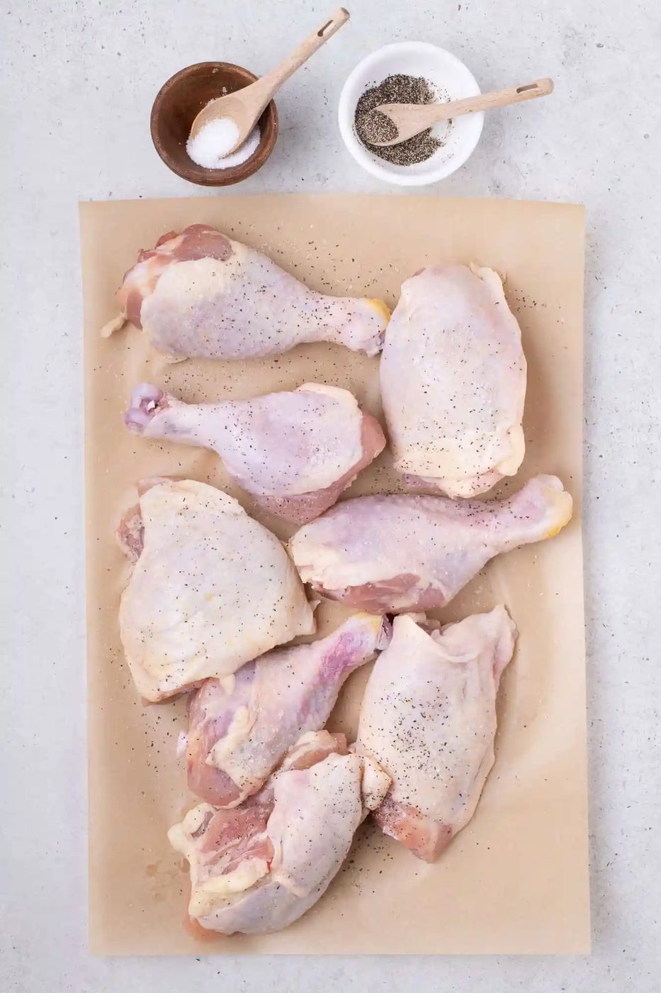 Chicken, not yet browned, on brown parchmenet.