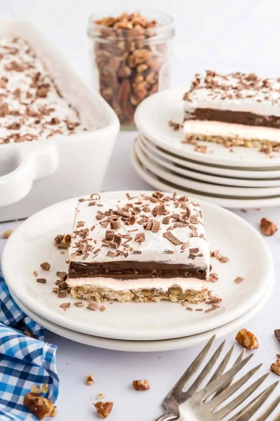 Slice of chocolate delight on a white plate, another slice in background.