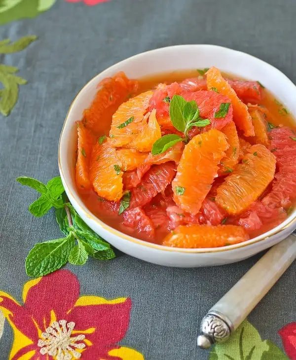 Citrus salad in round white bowl, on floral cloth.