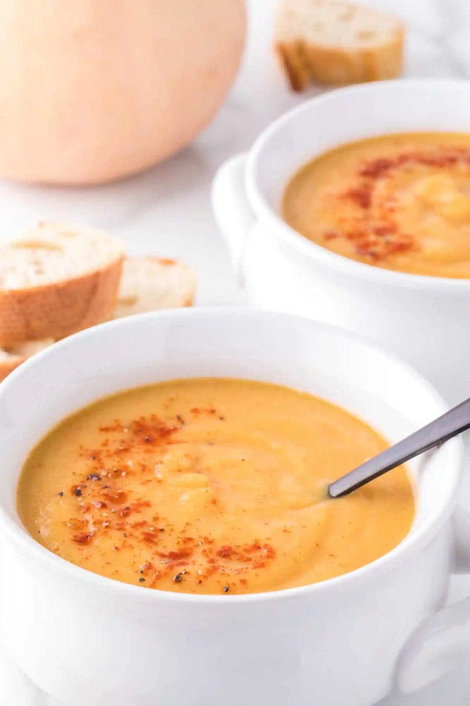 Soup and spoon in a bowl, soup garnished with paprika.