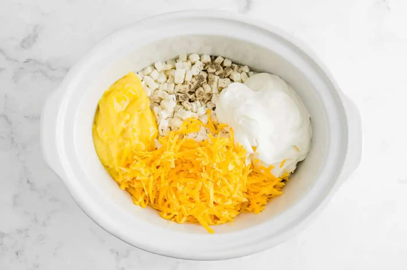 Ingredients, not mixed together, in a slow cooker.
