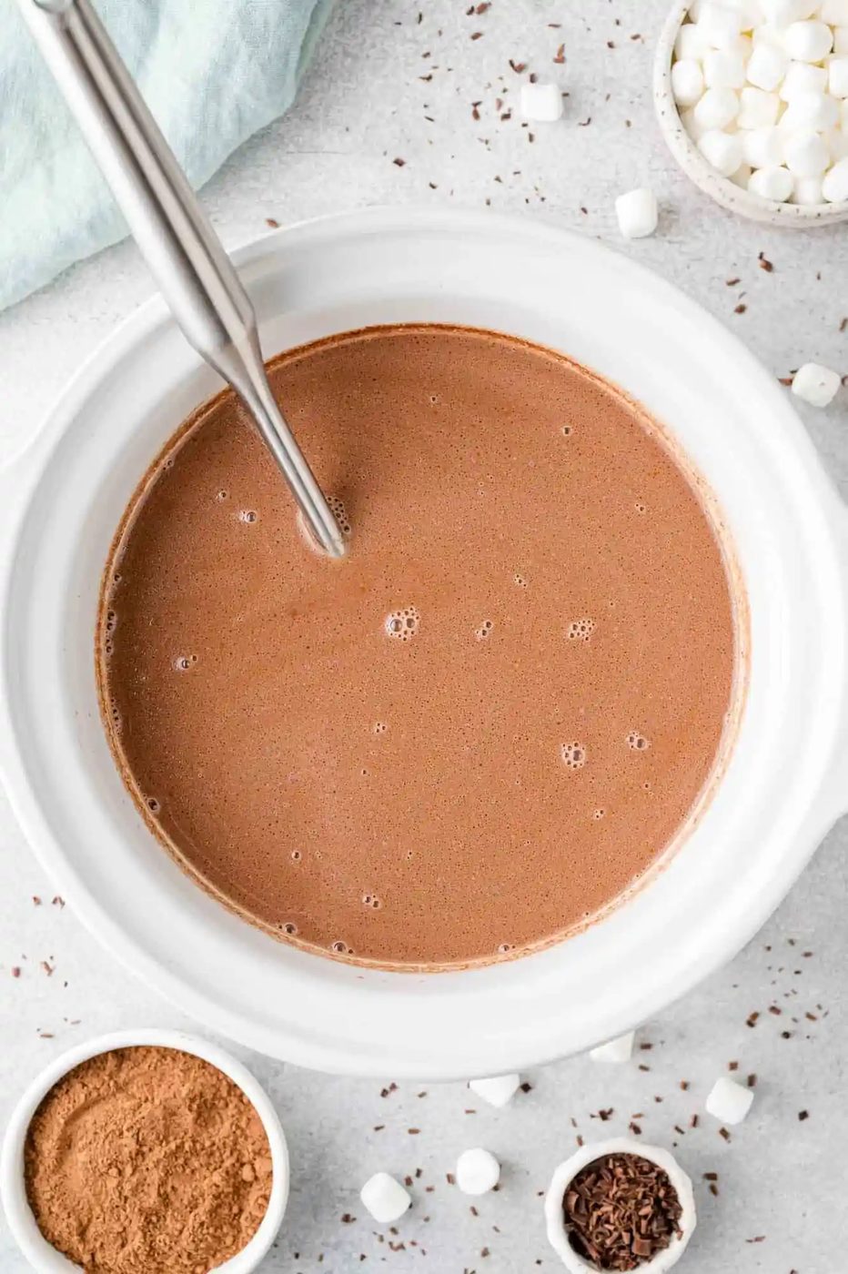 Overhead view of hot chocolate in a slow cooker, surrounded by mini marshmallows.