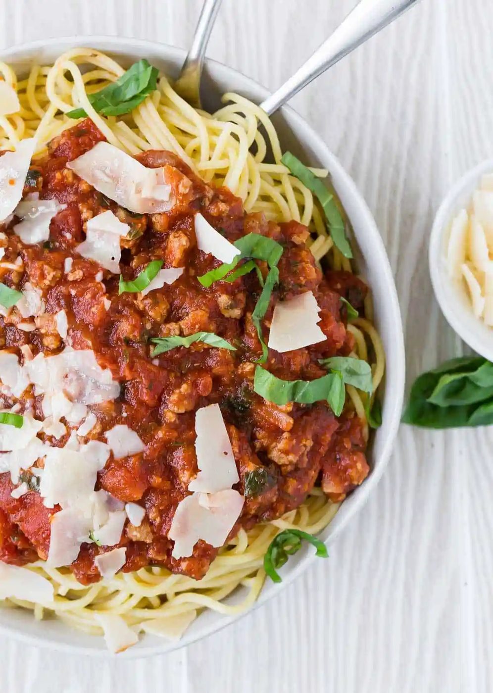 Overhead view of a large white bowl filled with spaghetti and meat sauce.
