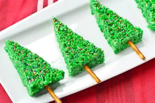 Christmas tree cookies arranged on rectangular white platter, on red cloth.