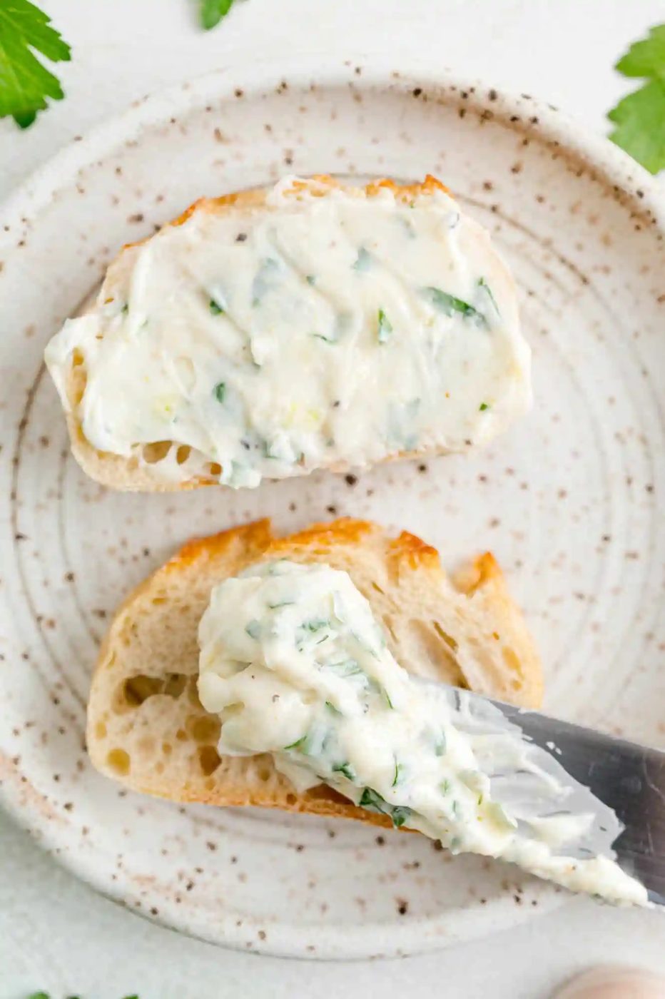 Garlic butter being spread on a small piece of bread.