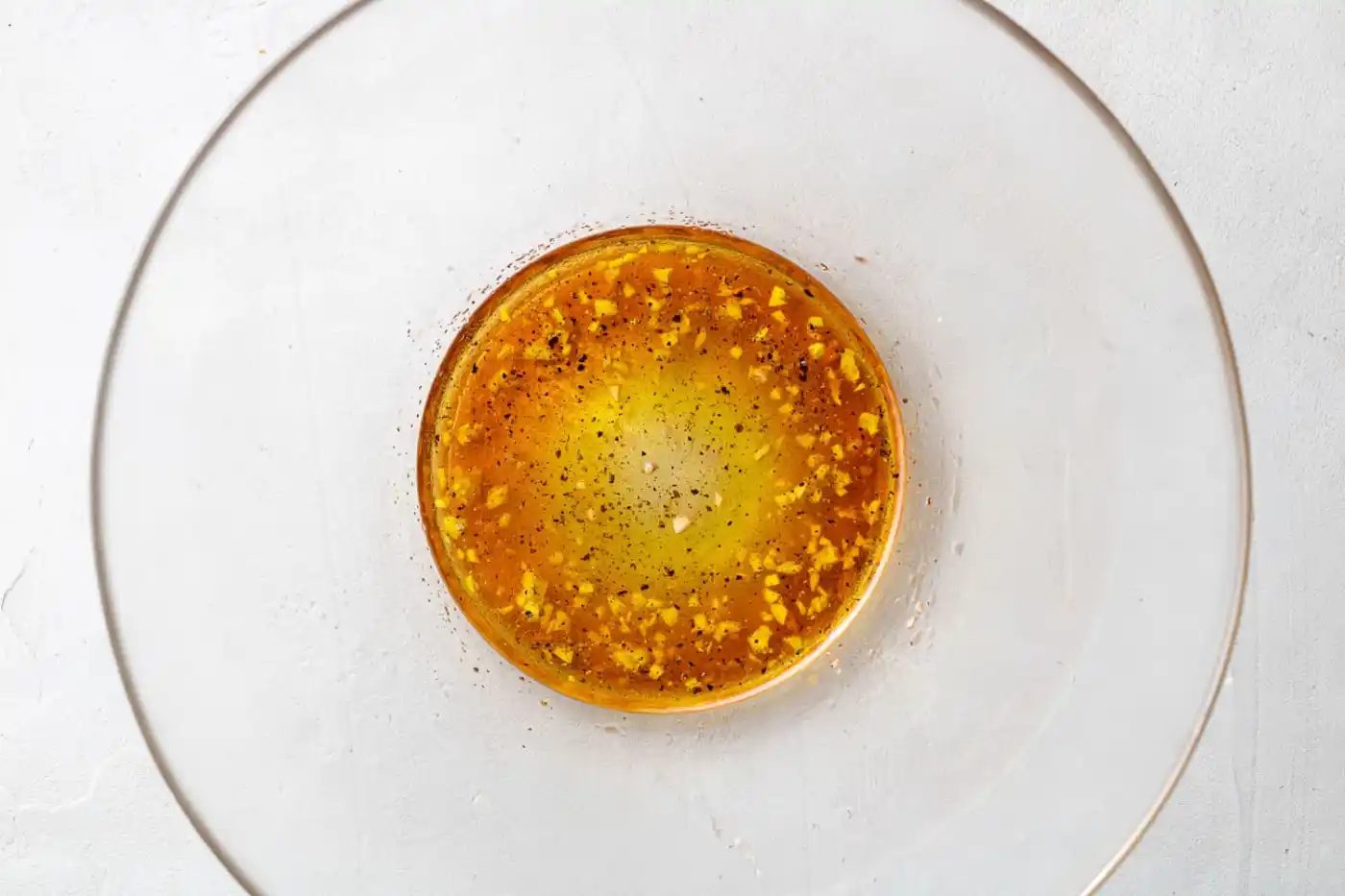 Salad dressing in a large clear glass bowl.