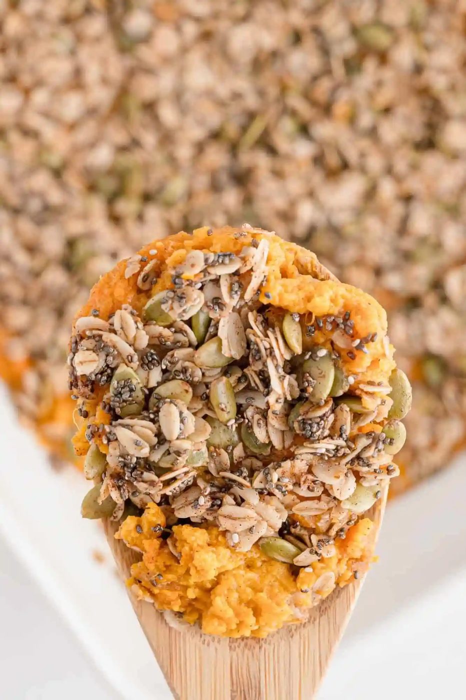 Lighter sweet potato casserole on a wooden spoon over the rest of the casserole.