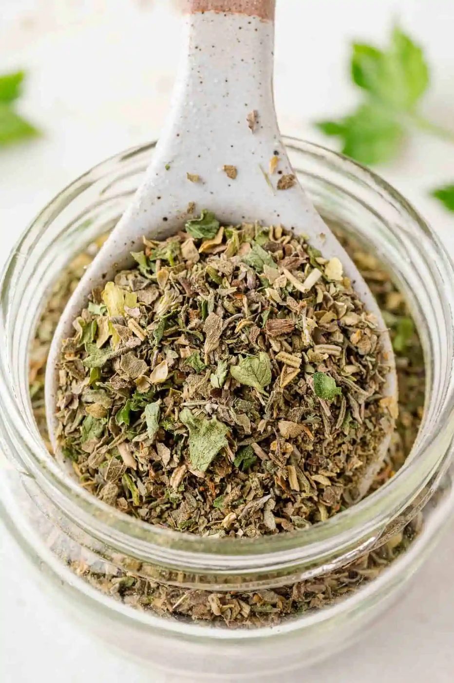 Italian seasoning, being scooped from a jar.