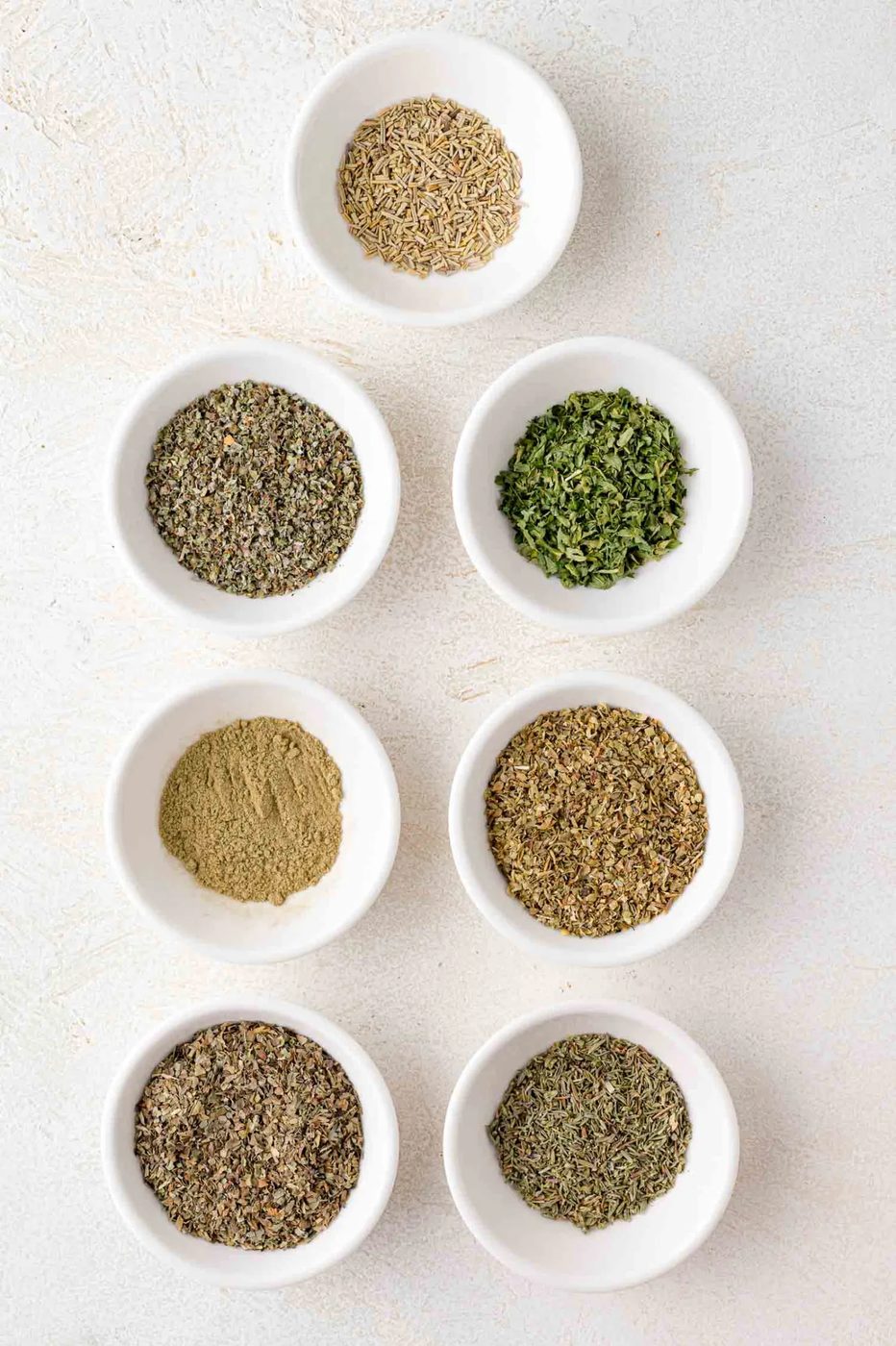 Italian seasoning ingredients in individual small glass bowls.