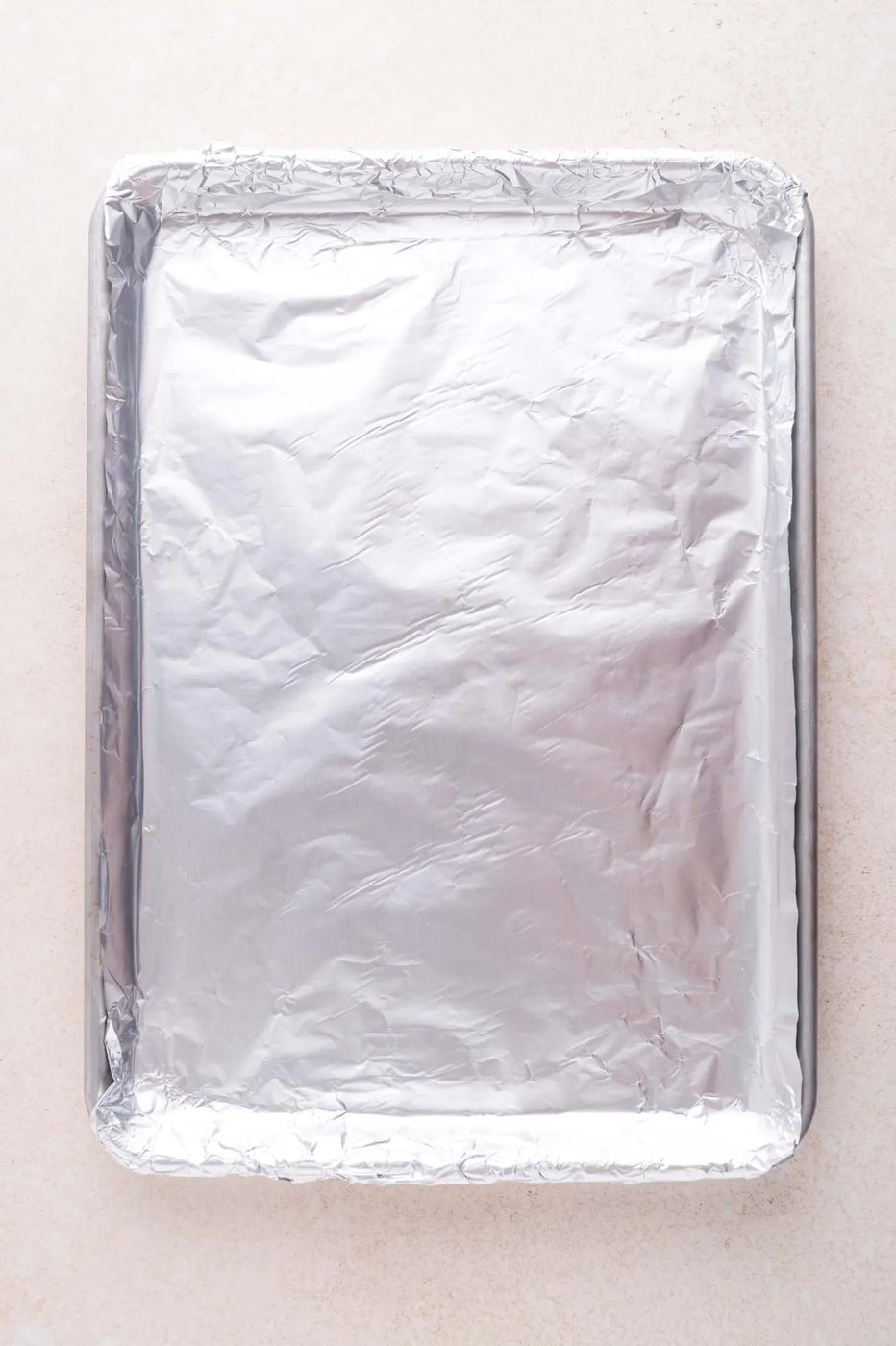 A rectangular baking sheet lined with aluminum foil sits on a light-colored surface.