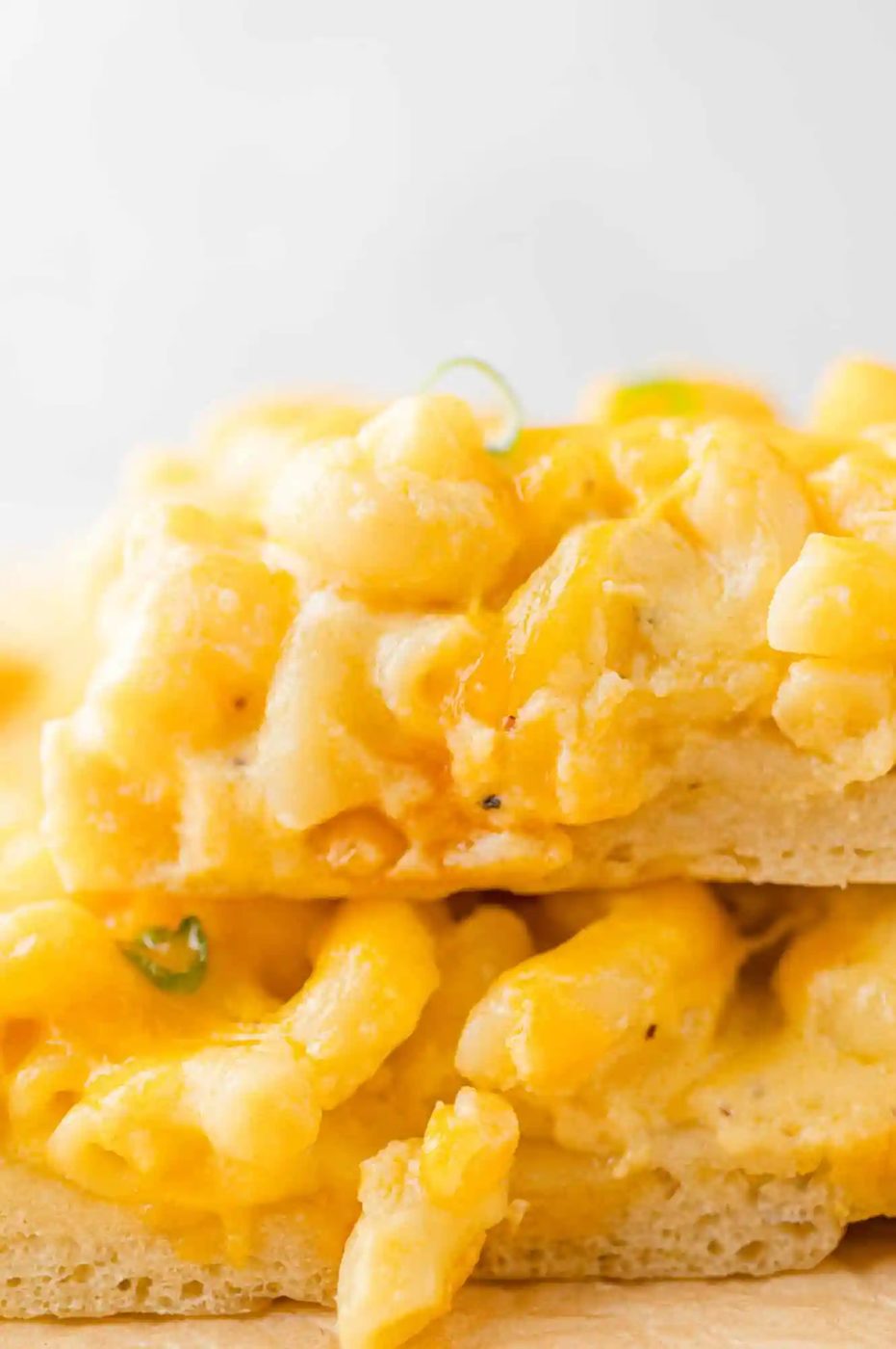 Slices of mac and cheese pizza stacked on top of each other.