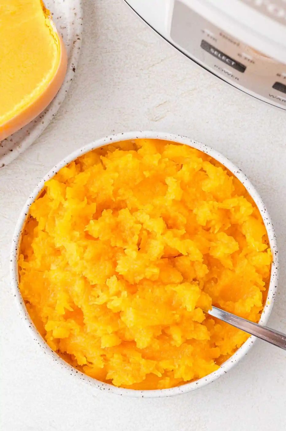 Cooked butternut squash in a large white bowl.