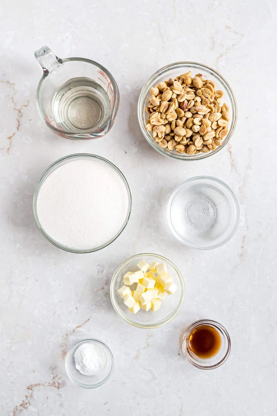 Top view of ingredients for recipe, including peanuts, sugar, cubed butter, and more.,