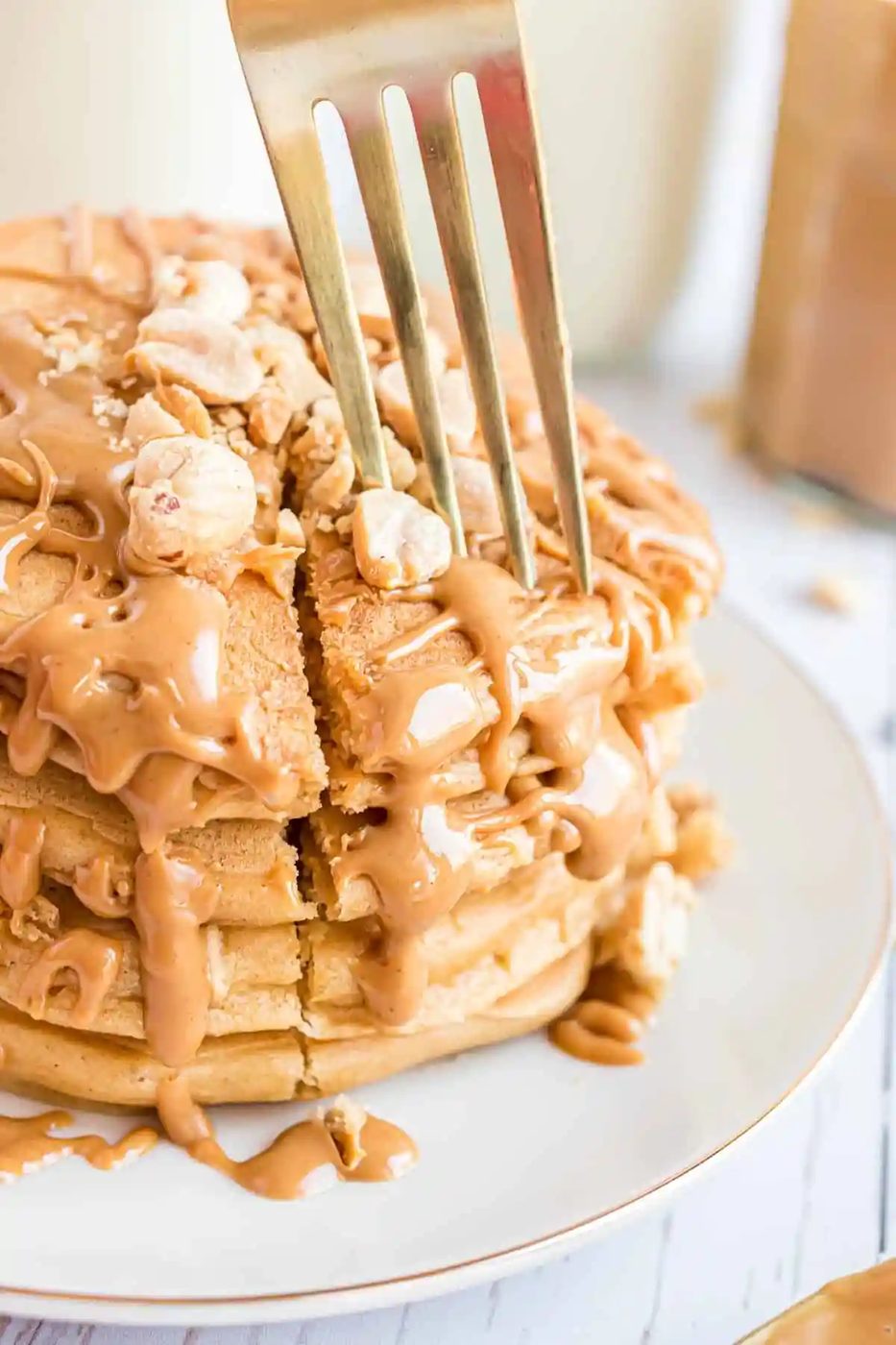A stack of pancakes with peanut butter syrup and nuts.
