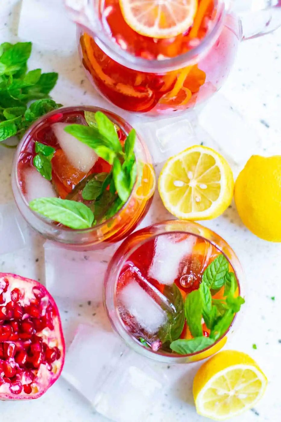 Overhead view of two glasses of sparkling pomegranate punch, garnished with fresh pomegranate and mint leaves.
