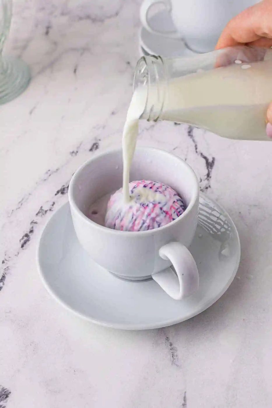 Milk being poured over a white chocolate hot cocoa bomb.