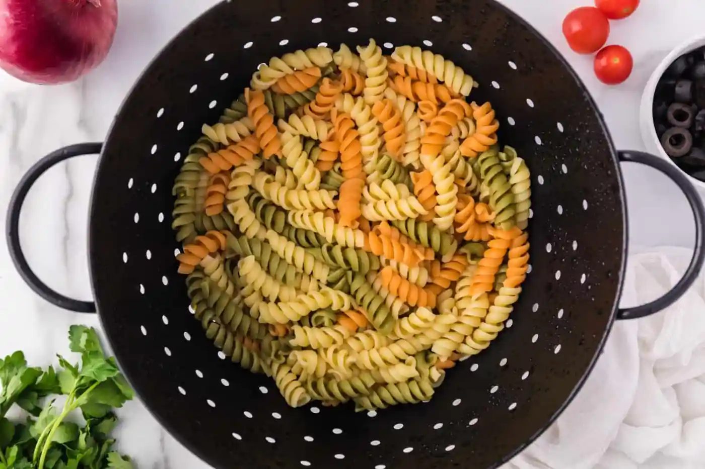 Tricolor rotini in a black colander.