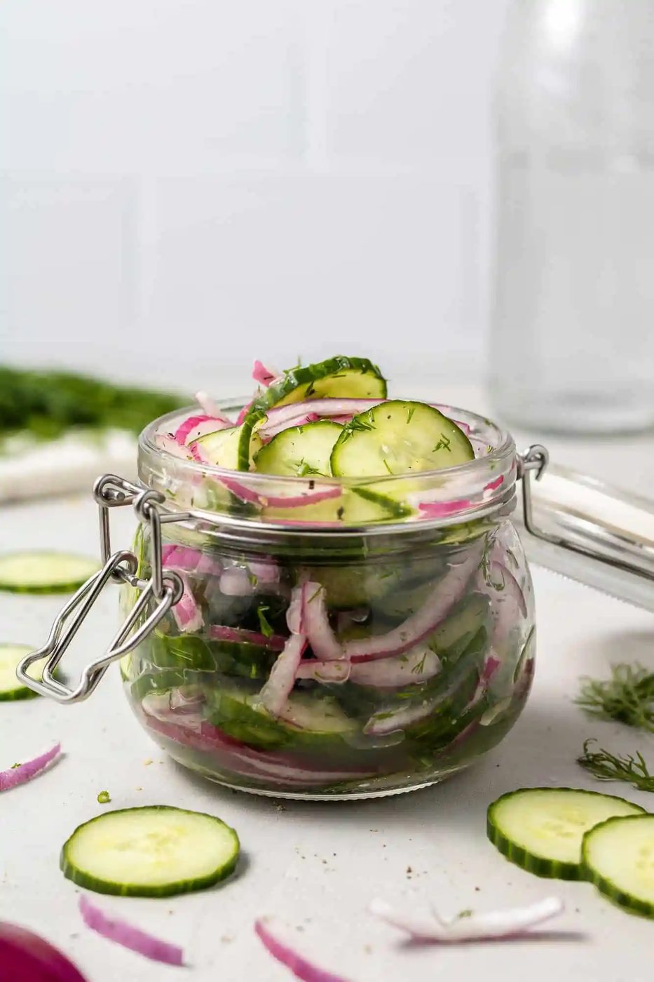 Jar filled with sliced cucumbers and onions in a brine.