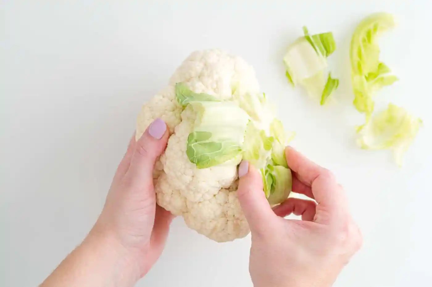 Leaves being removed from a head of cauliflower.