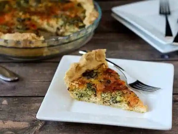 Slice of quiche on a square white plate.