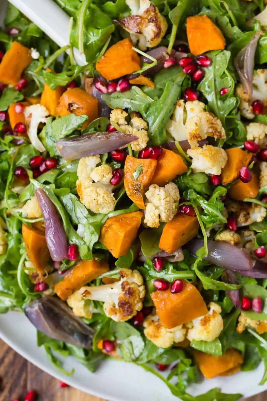 Close up of arugula salad with roasted cauliflower and sweet potatoes.