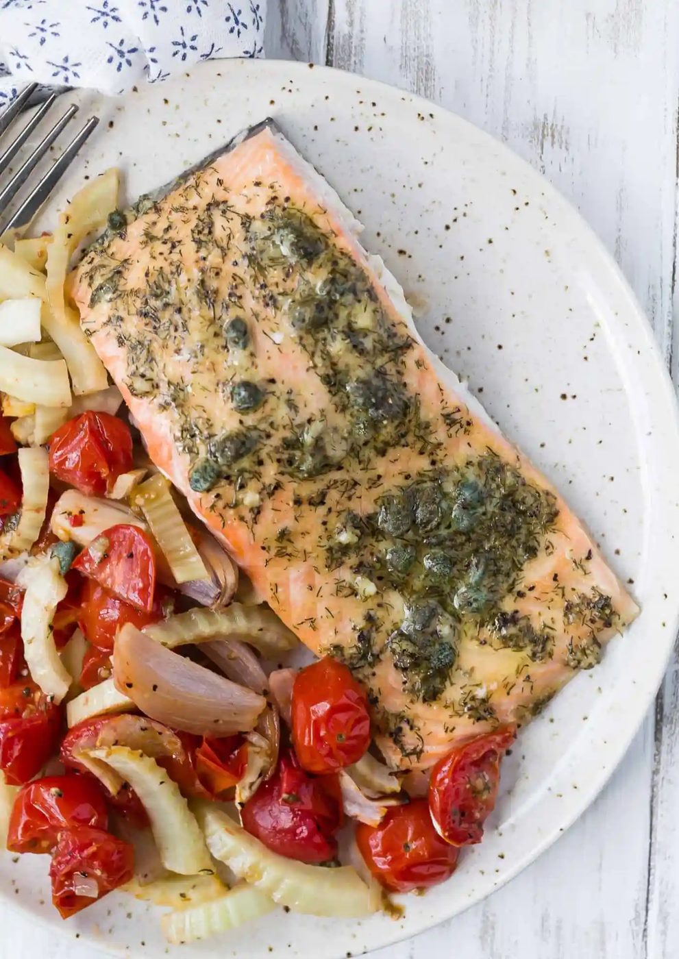 Plated cooked salmon with roasted tomatoes and fennel.