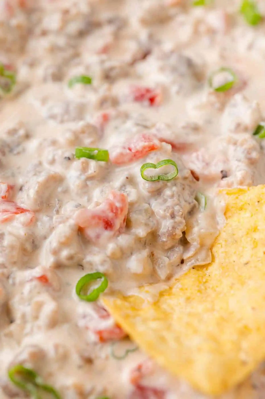 Sausage dip on a tortilla chip.