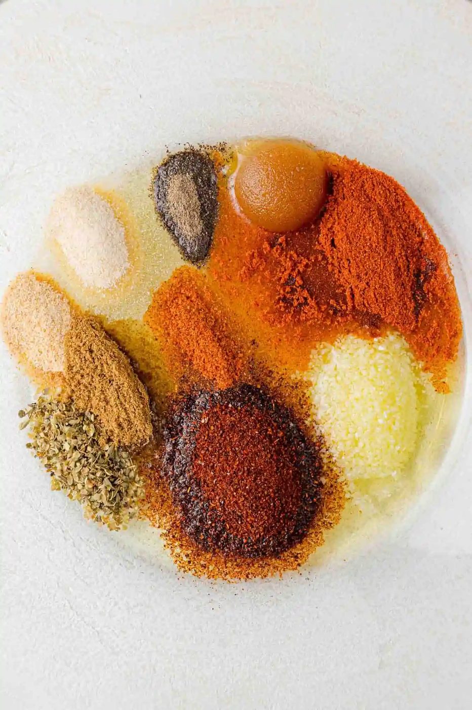 Spices and oil in a bowl, not yet mixed together.