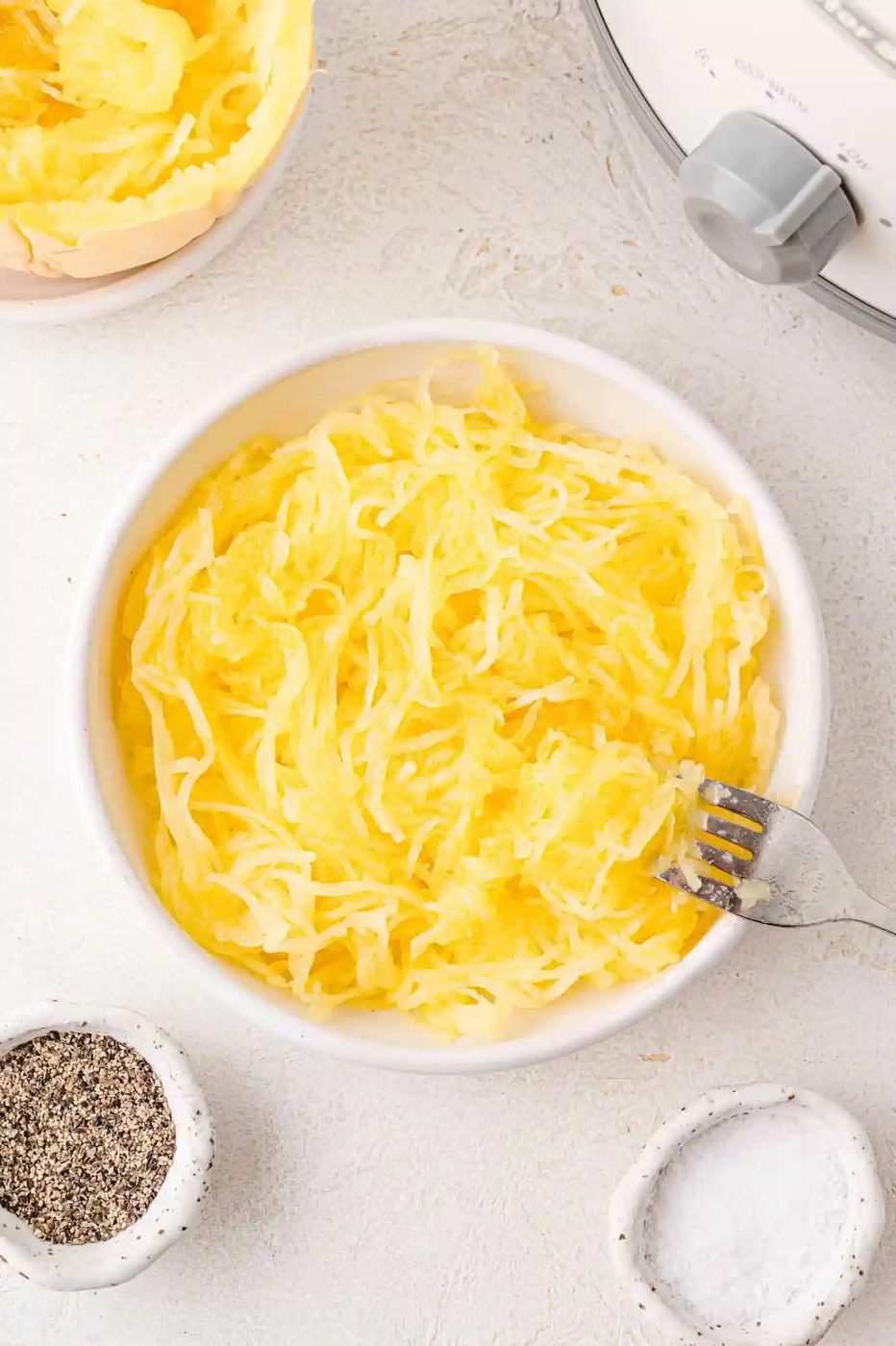 Spaghetti squash strands in a white bowl with a fork.