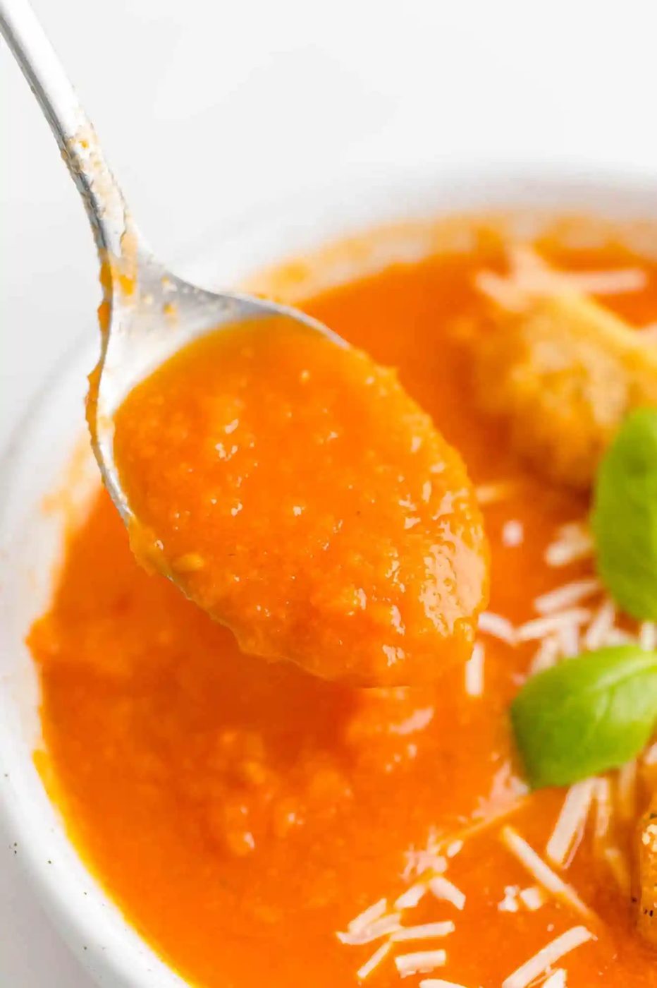 Close up view of tomato soup on a spoon.