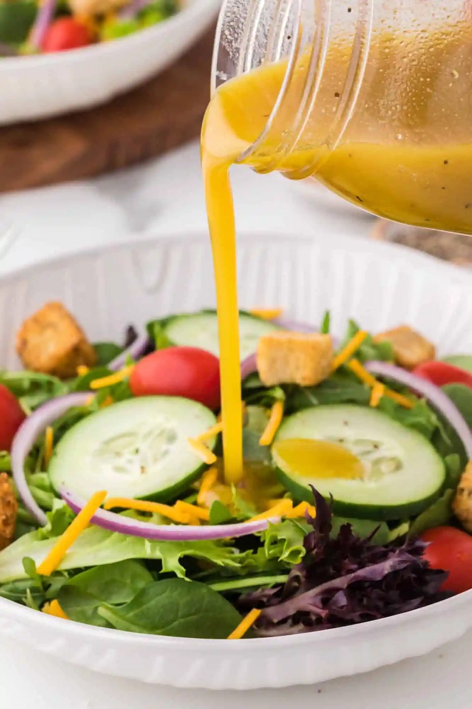 Vinaigrette being poured on a green salad.