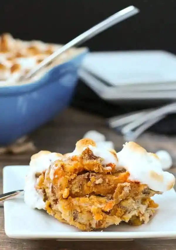 Close up of single piece of bread pudding on square white plate with fork.