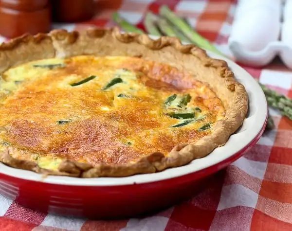 Turkey sausage and asparagus quiche in a red pie plate.