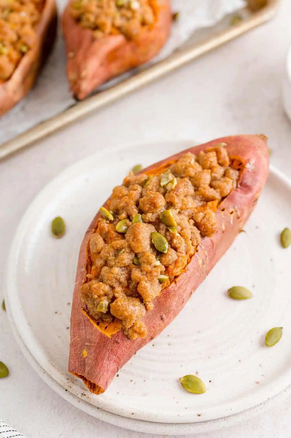 Twice baked sweet potato on white plate with pepitas garnishing.