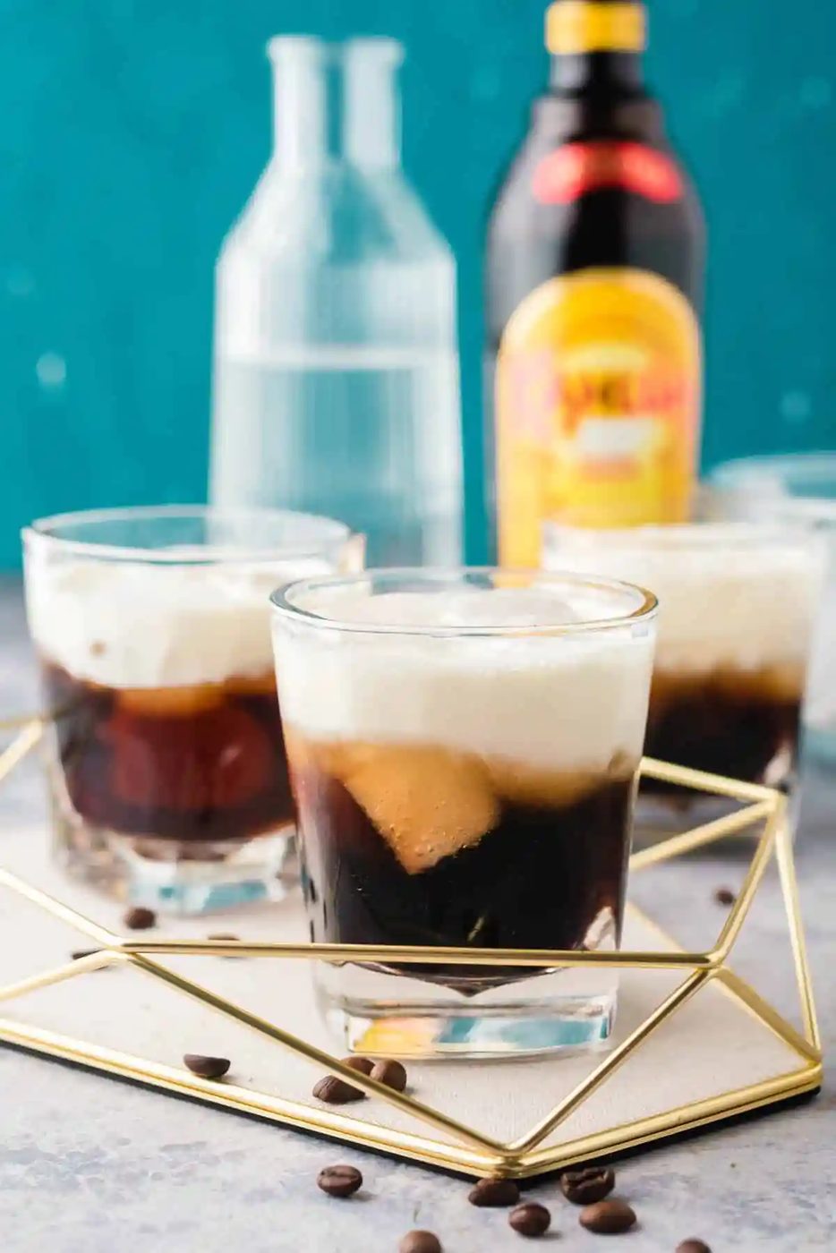 Kahula, vodka, and cream cocktails on a tray with a blue background.