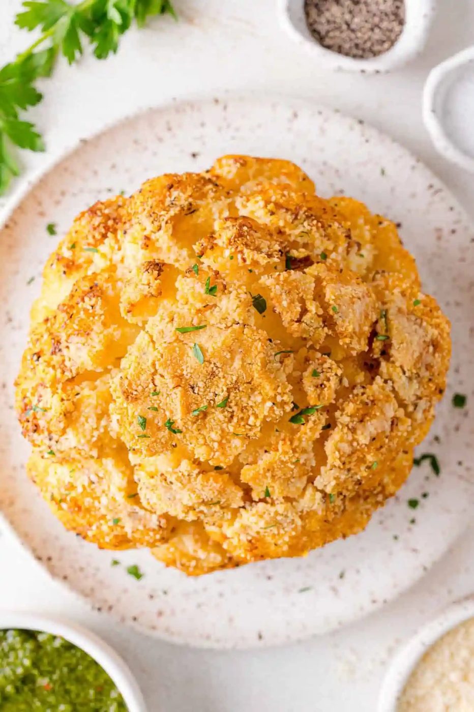Overhead view of a whole roasted cauliflower on a plate.