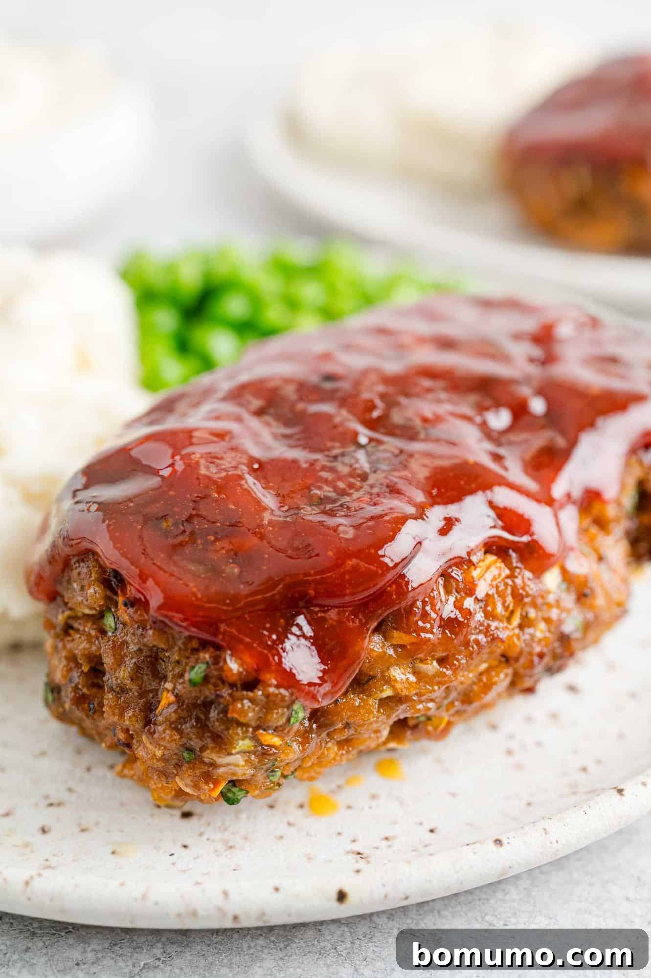 A whole air fryer meatloaf resting on a cutting board, beautifully glazed and ready to be sliced.