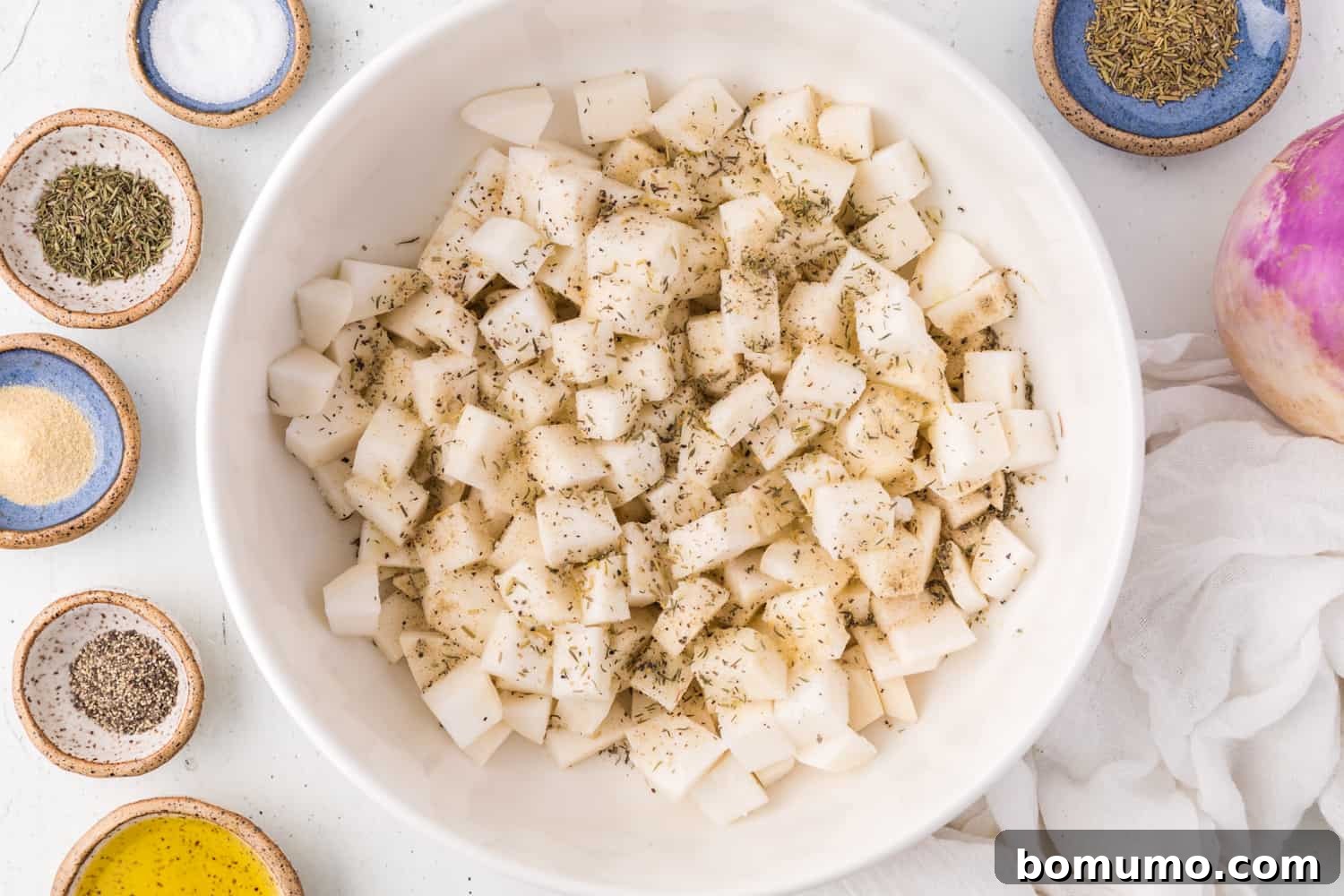 Turnips in a bowl, thoroughly coated with herbs and spices.