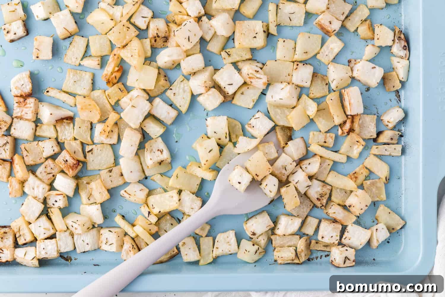 Golden-brown, roasted turnips on a blue sheet pan, fresh out of the oven.