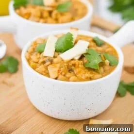 Easy chicken chili in white bowl with handle garnished with parsley leaves.