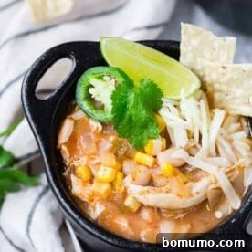 Image of pressure cooker white chicken chili in a black bowl with garnishes like cilantro and sour cream.
